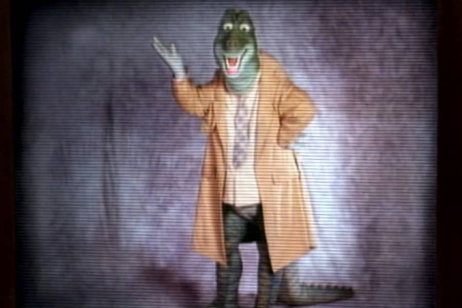 a male dinosaur in a shirt and tie and trenchcoat