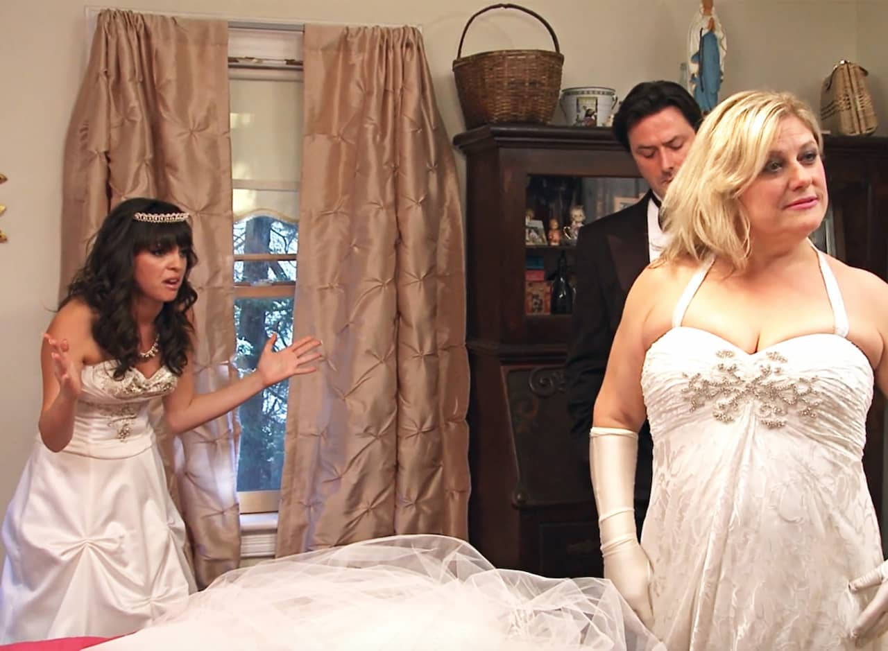 bride is aghast at her mother who is wearing her own fancy white gown with gloves