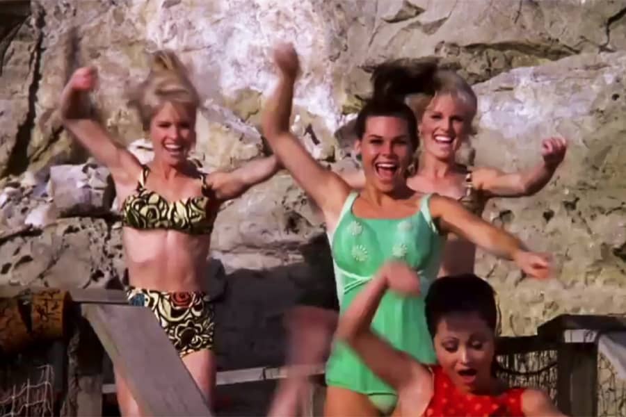 women in swimsuits dance at the beach