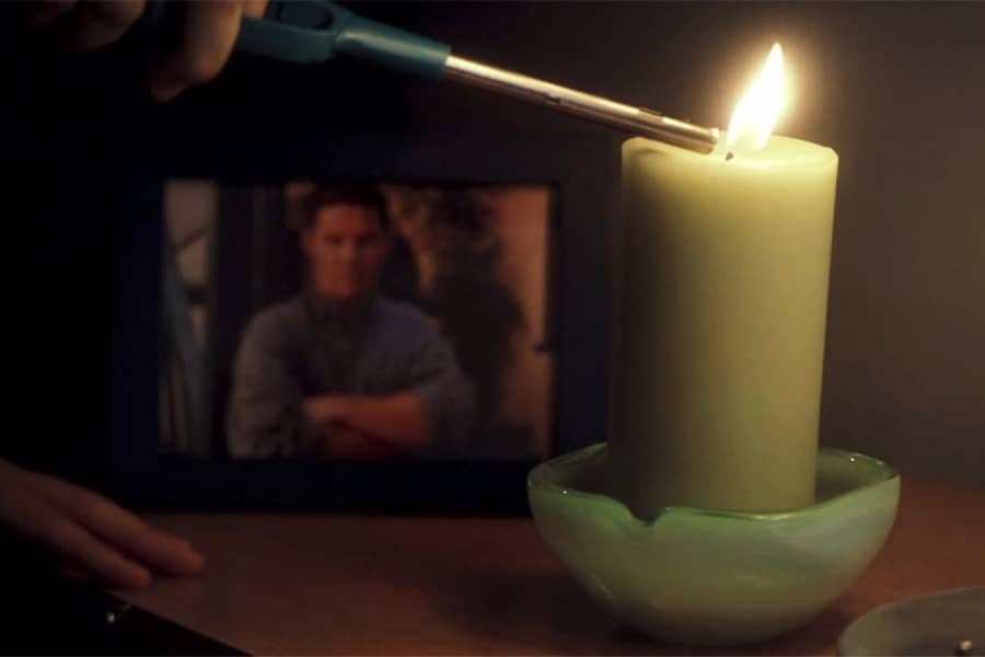lighting a candle next to a blurry photo of a man