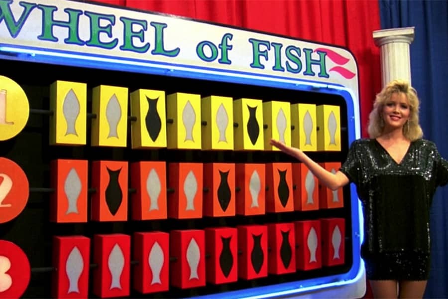 show hostess presents a Wheel of Fish game board with differently colored rows of fish iconography