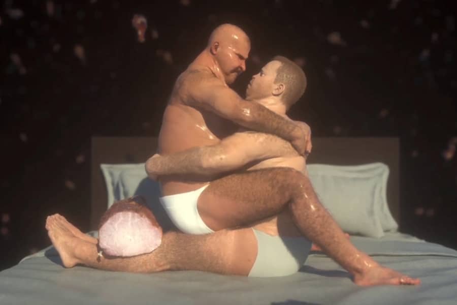 one man is straddling the other on a bed, the ham is resting on the guy’s legs