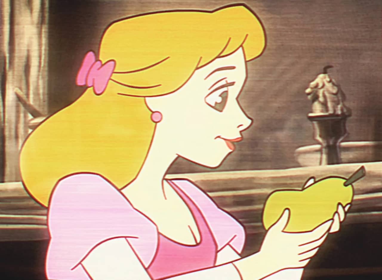 a blonde Disney-esque woman is about to take a bite of a pear