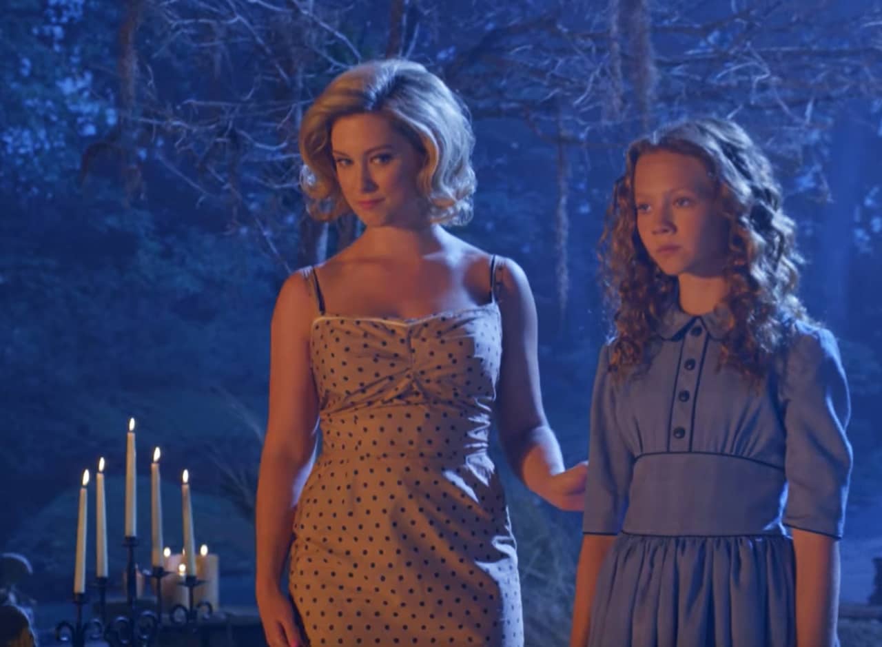 a blonde woman with a young girl in the woods with lit candles