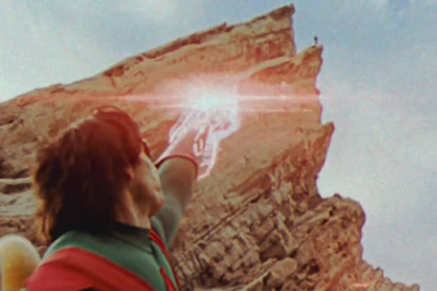 Wonder Man aiming an electric bolt at an alien up on a cliff