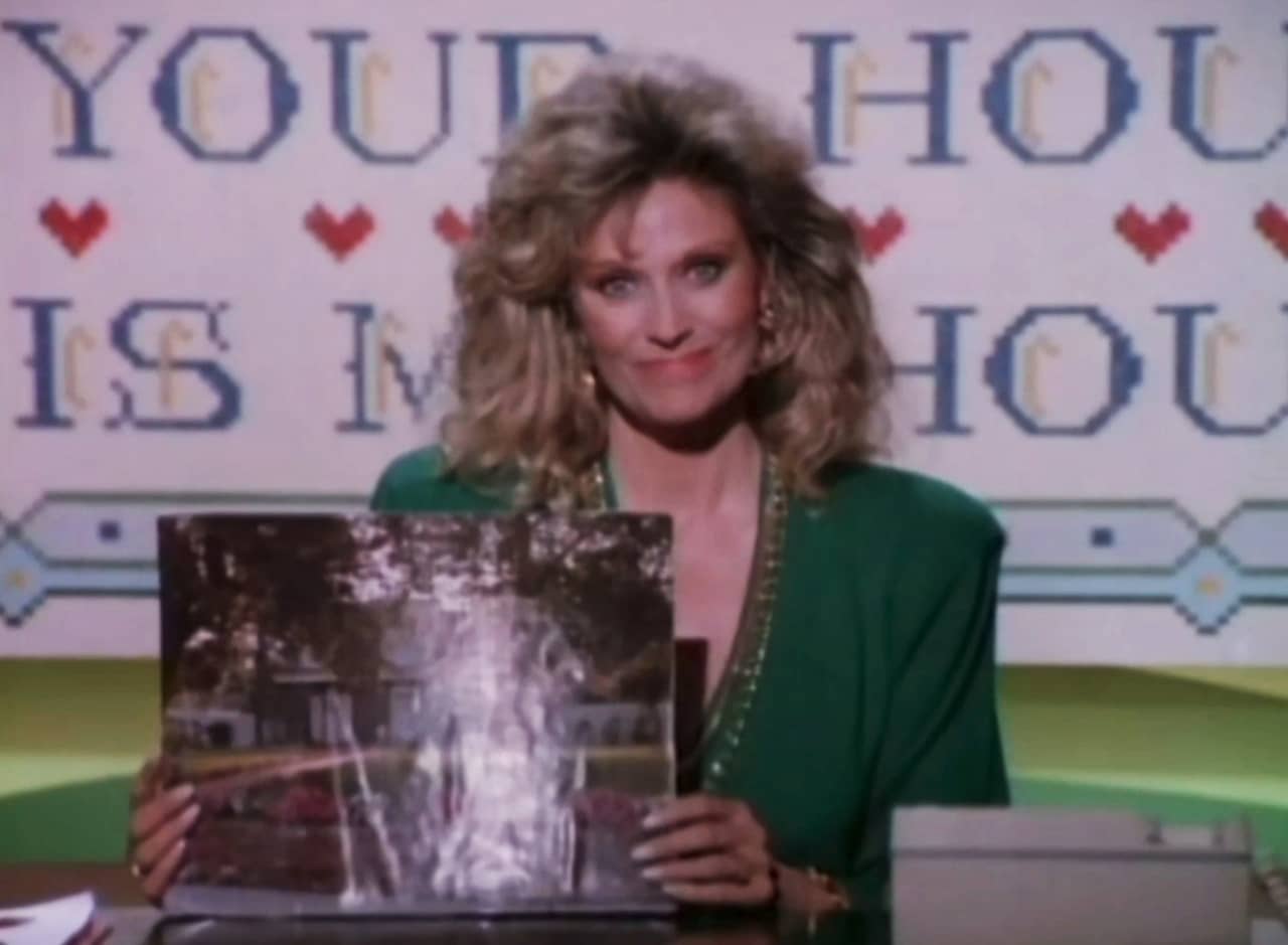Joanna Loudon holding up a photo of a house